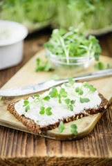 Wooden table with healthy food (slice of bread, cream cheese and fresh cutted cress)