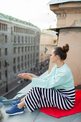 Beautiful lonely girl sitting on the roof in the old town of dreams.