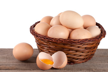 eggs on a wooden table in a wicker basket on a white background