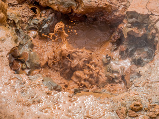 Boiling mud pools, known as mud pots, erupt near fumaroles in a volcanic area of Nicaragua, Central America. Their reddish brown color comes from iron deposits in the ground.
