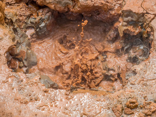 Boiling mud pools, known as mud pots, erupt near fumaroles in a volcanic area of Nicaragua, Central America. Their reddish brown color comes from iron deposits in the ground.