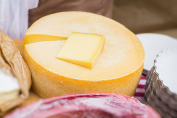 Close-up of Cheese wheel and cut piece on market counter. Dairy produce