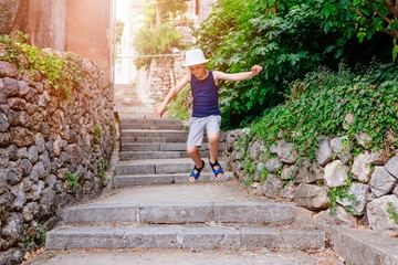 Child in white hat walking on narrow street of old town