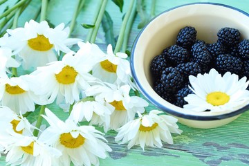 Delicious fresh blueberries in a bowl and flowers  