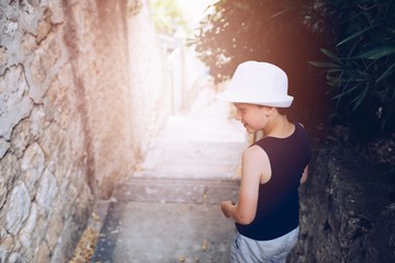 Child in white hat walking on narrow street of old town
