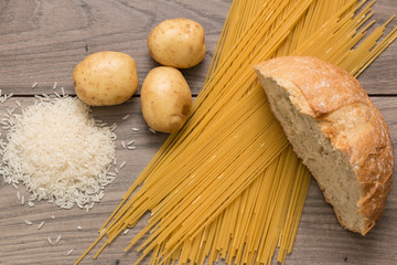 Spaghetti, rice, potatoes, and bread, on a wooden table