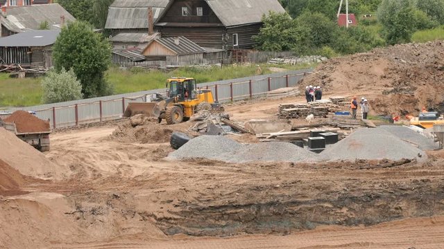 Dump truck unload pit sand into a large pile of sand of construction pit. Superintendents dressed in white helmets solve problems of construction