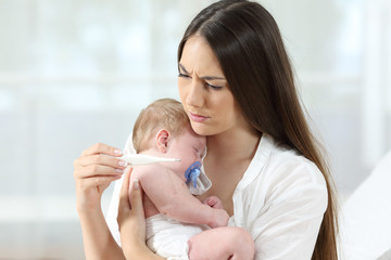 Mother checking thermometer with an ill baby