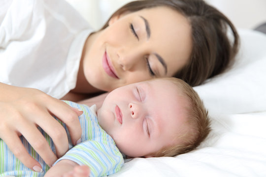 Mother and baby sleeping together on bed
