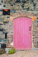 Old red wooden door on stone wall of an old building.