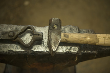 Hammer and tongs on anvil in blacksmith shop