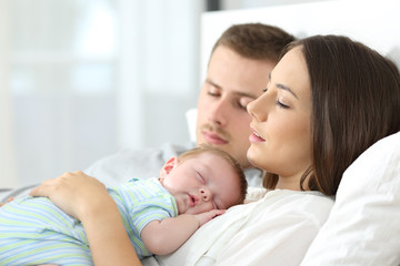 Tired parents sleeping with their baby