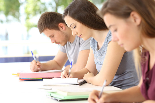 Three students taking notes during a class