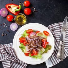 Vegetable meat salad in a plate against a dark background. Selective focus. Top view. Copy space