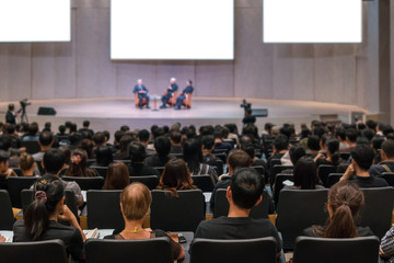 Rear view of Audience over the speakers on the stage in the conference hall or seminar meeting,...