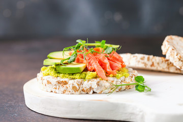 Sandwich crispbread with avocado and a salmon against a dark background. Selective focus. Copy space