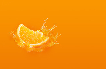 Slide cut piece of orange drop on orange background with orange juice splash water with copy space
