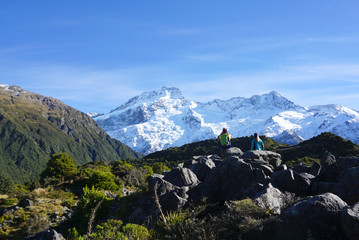 Hiker standing on the meadow with snow mountain background