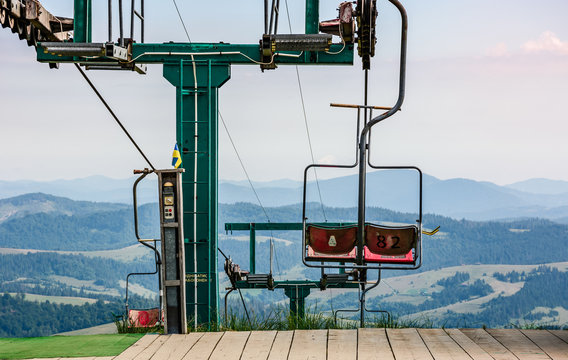 empty ski elevator with red chairs on top of a hill