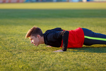 Fototapeta na wymiar Young athlete doing an exercise in training on a green football field
