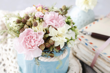 Bouquet of pink carnations and yellow Kalanchoe blossfeldiana flowers in blue ceramic vase.