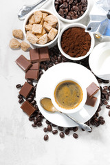 cup of espresso, ingredients and sweets on white background, vertical, top view
