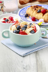 Bowl of yogurt with muesli and fresh fruits: strawberries, blueberries and bananas.