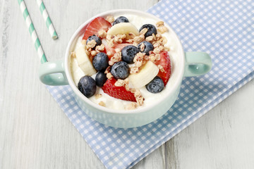 Bowl of yogurt with muesli and fresh fruits: strawberries, blueberries and bananas.