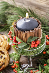 Candle decorated with cinnamon sticks and red berries (cotoneaster horizontalis).