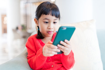 Asian little girl playing cellphone at home