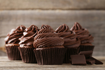 Tasty cupcakes with pieces of chocolate on grey wooden table