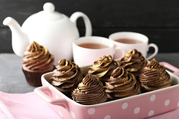Tasty chocolate cupcakes in baking dish on grey background