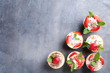 Dessert tartlets with strawberries on grey wooden table