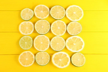 Slices of limes and lemons on yellow wooden table