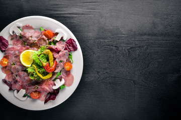 Carpaccio of beef, vegetables, cheese, spices, to Wooden background. Top view. Free space