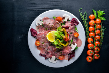 Carpaccio of beef, vegetables, cheese, spices, to Wooden background. Top view. Free space