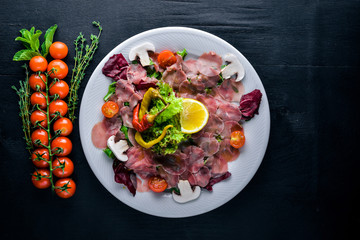Carpaccio of beef, vegetables, cheese, spices, to Wooden background. Top view. Free space