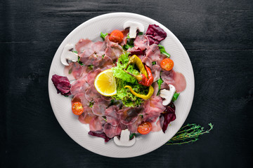 Carpaccio of beef, vegetables, cheese, spices, to Wooden background. Top view. Free space