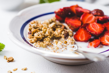 Muesli with milk and fresh strawberry in a white plate