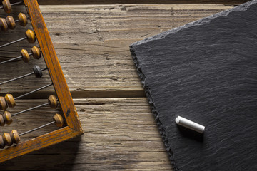 Old wooden scratched vintage decimal abacus and blank blackboard with copy space and chalk on a wooden desktop . Top view. Flat lay. Mockup
