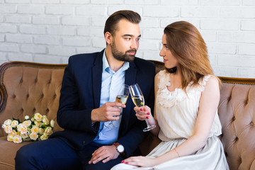 young beautiful couple celebrating something with champagne at home