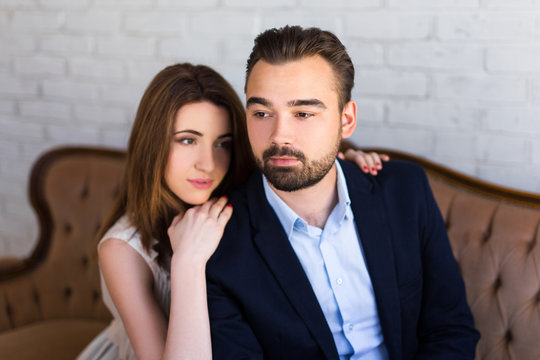 relationship concept - portrait of young beautiful couple sitting on sofa