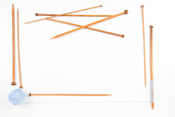 Knitting needles and blue yarn ball frame on white background