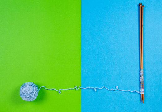 Blue yarn ball and knitting needles on colorful background