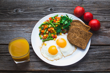 two fried eggs on the plate and vegetables