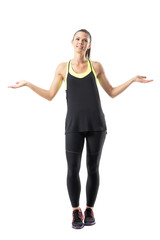 Confused young athletic sporty woman in leggings shrugging shoulders looking up. Full body length portrait isolated on white background.
