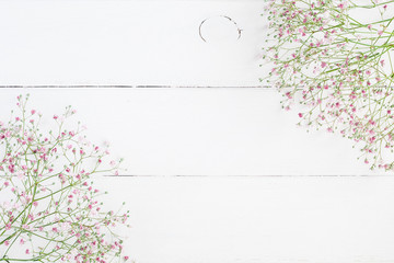 Floral frame made of pink gypsophila flowers on white wooden background. Flat lay, top view, copy...