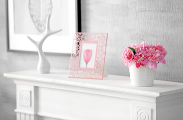 Interior of light room with beautiful peonies in vase on mantelpiece