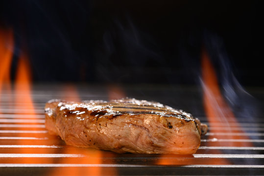 Grilled pork steak on the flaming grill
