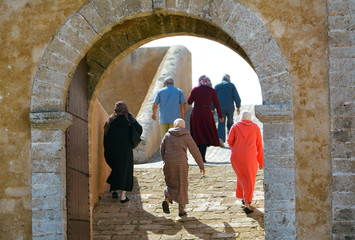 Fototapeta na wymiar Moroccans walk on streets of old Medina in clear sunny day